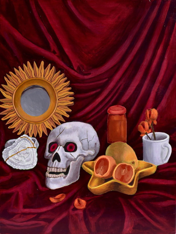 There’s a star-shaped plate holding orange and a mango. To the left is a skull. Items are sitting on a red velvety fabric.
